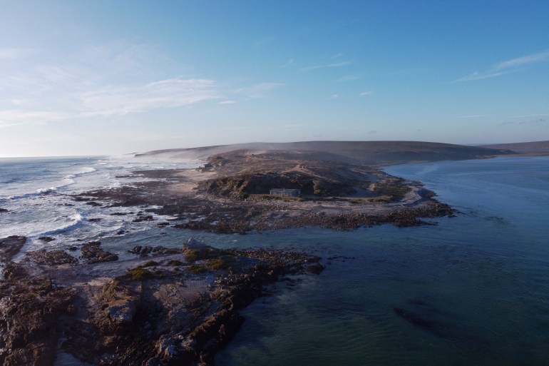 This aerial view shows the Olifants Estuary in Papendorp, near Doringbaai, on September 22, 2022. With pink flamingos, white beaches and blue ocean waters, a stretch of South Africa's west coast has become a battleground between mining firms and environmentalists worried that diggers will raze the nature. Diamonds, zircon and other minerals have long been extracted in the coastal area near the Olifants river, which flows into the Atlantic Ocean about 300 kilometres north of Cape Town. But plans to expand mining and prospecting have angered surfers, animal lovers and residents of the sparsely populated rural region, who have pushed back with lawsuits and petitions. (Photo by WIKUS DE WET / AFP)