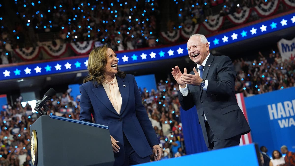 Kamala Harris and Tim Walz smiling and waving at rally