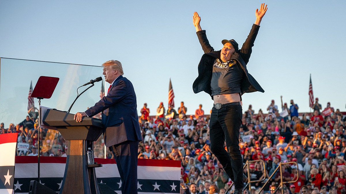 Elon Musk leaps into the air as Donald Trump stands at the podium