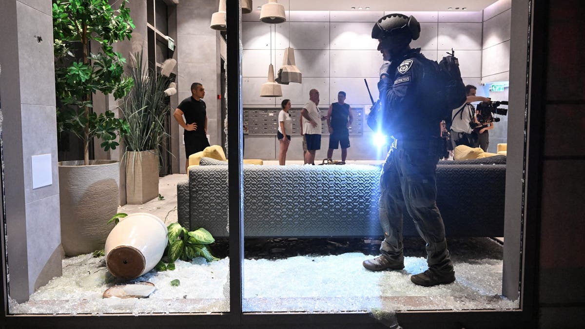 An Israeli police officer inspects the damage to a residential building caused by a rocket fired towards Israel from Lebanon, amid cross-border hostilities between Hezbollah and Israel, in Haifa, Israel, on Oct. 7, 2024.