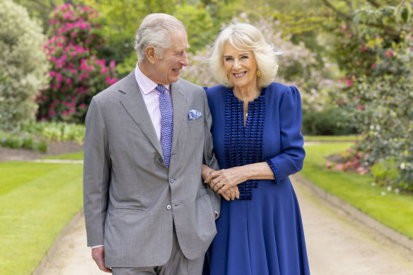 King Charles III and Queen Camilla stand in Buckingham Palace Gardens.