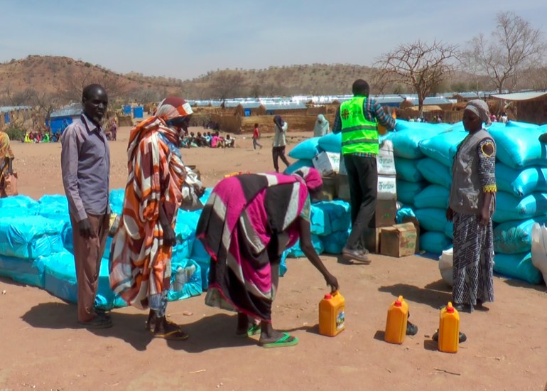 Sudanese refugees stand around food aid in Metche camp, Chad