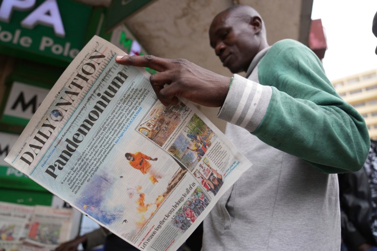 kenyan man reads newspaper about protest