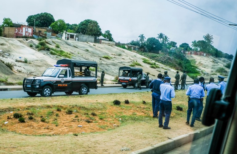 Police officers stand on a street in Maputo amid protests