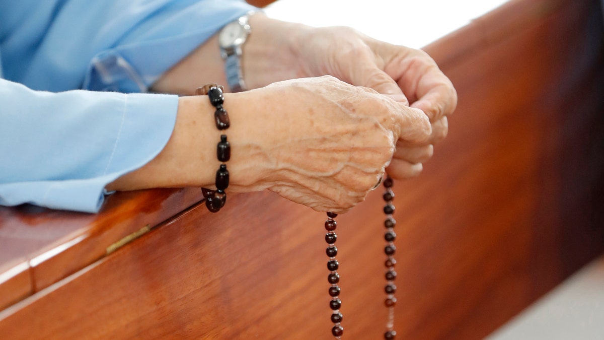 A woman's hands holding rosary