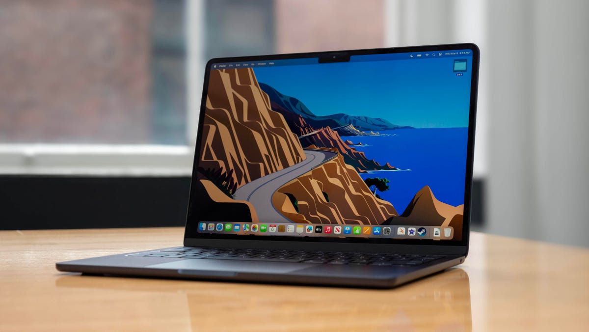 Apple MacBook Air M3 13-inch laptop on a wood table with windows in the background.