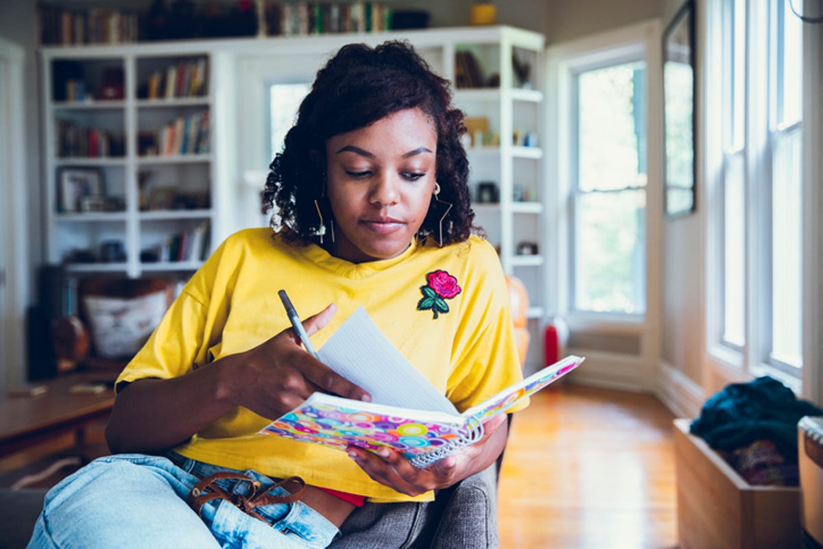 Young woman lounging in a chair, looking through her planner.