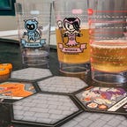 Board game tiles on a table with beer glasses in the background