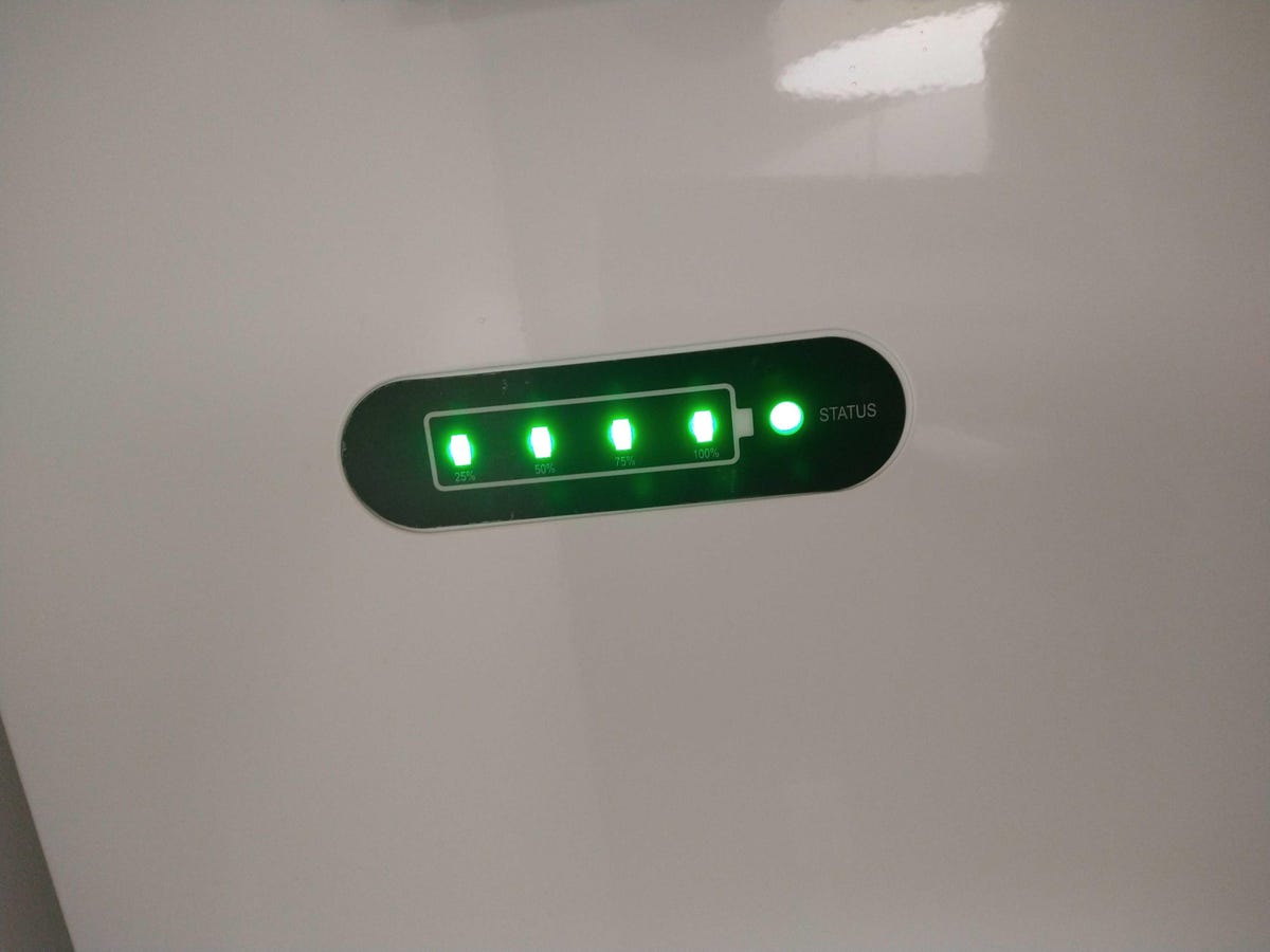 Five small green lights are lit up on a white device, with a black border around the lights.