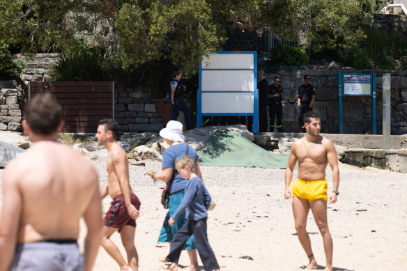 Beachgoers metres from the body which has been covered by a green tarpaulin.