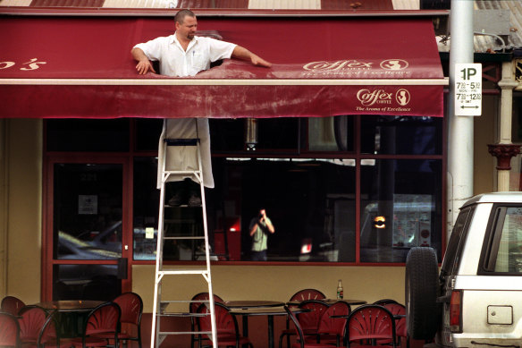 Harry Brosca inspects the damage after a soccer supporter threw a burning flag on top of the Papa Gino’s awning and burnt a hole in 2002.