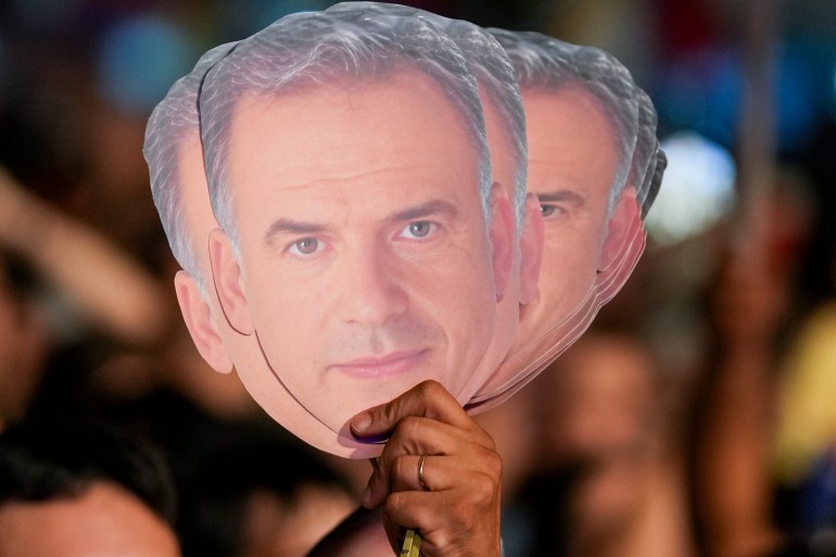 Supporters hold aloft multiple cut-outs of Yamandu Orsi's face.