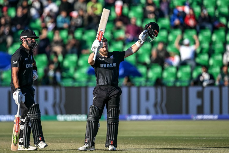 New Zealand's Kane Williamson (R) celebrates after scoring a century (100 runs) as his teammate Daryl Mitchell watches during the ICC Champions Trophy one-day international (ODI) semi-final cricket match between New Zealand and South Africa at the Gaddafi Stadium in Lahore on March 5, 2025. (Photo by Aamir QURESHI / AFP)