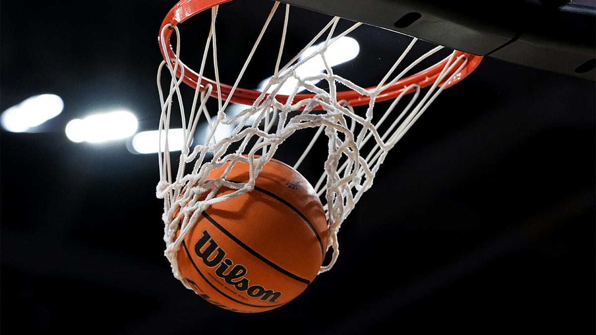 A basketball goes through a hoop in a college basketball game