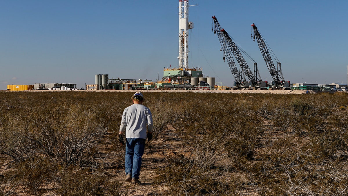 An oil worker walks toward a drill rig after placing ground monitoring equipment in the vicinity of the underground horizontal drill in Loving County, Texas. (Reuters/Angus Mordant)