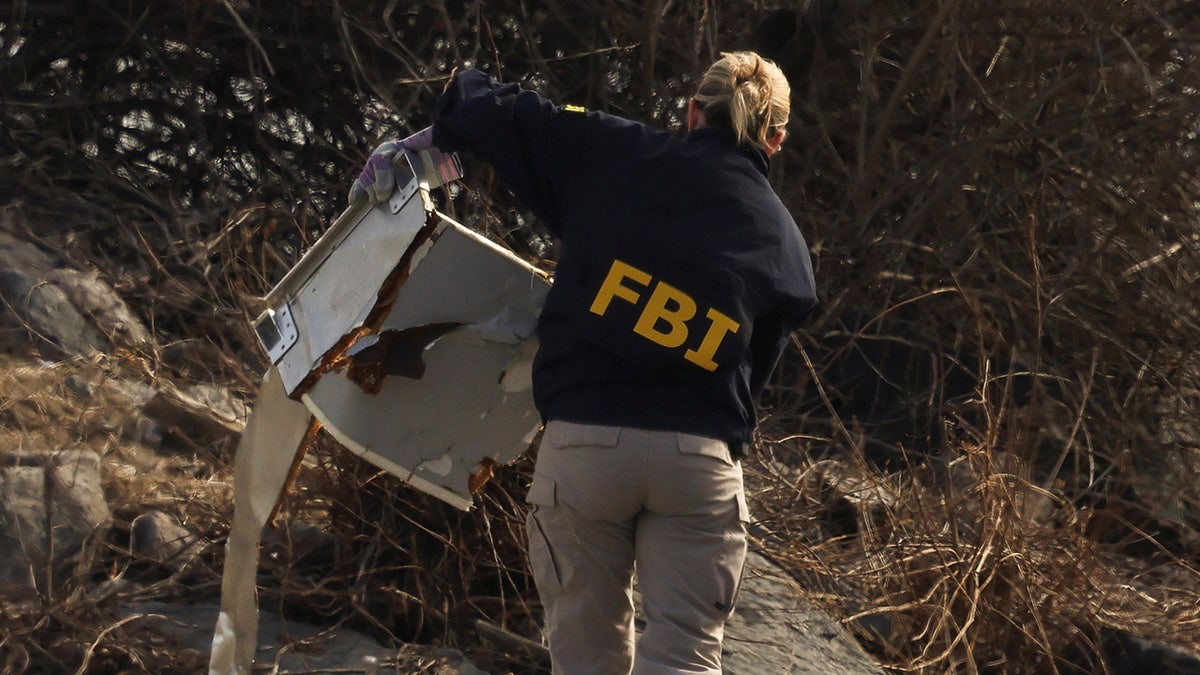 FBI agents stand near debris, after American Eagle flight 5342 collided with a Black Hawk helicopter