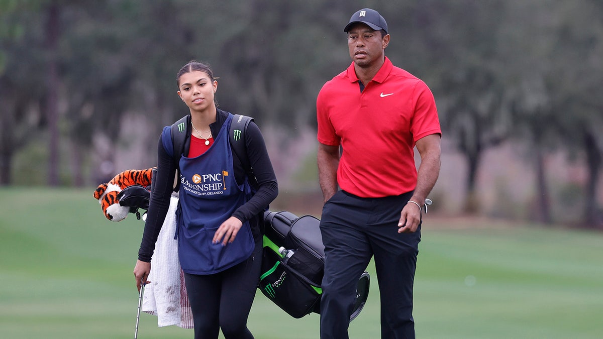 Tiger and Sam Woods walk on golf course