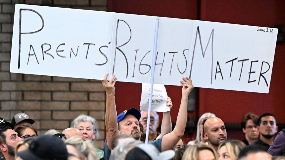 man holding 'parents rights matter' sign at meeting