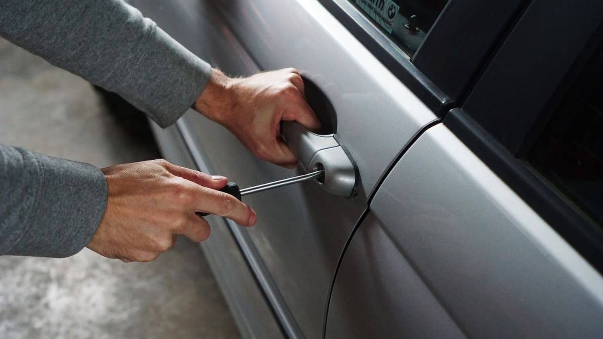 A car thief breaking into a vehicle
