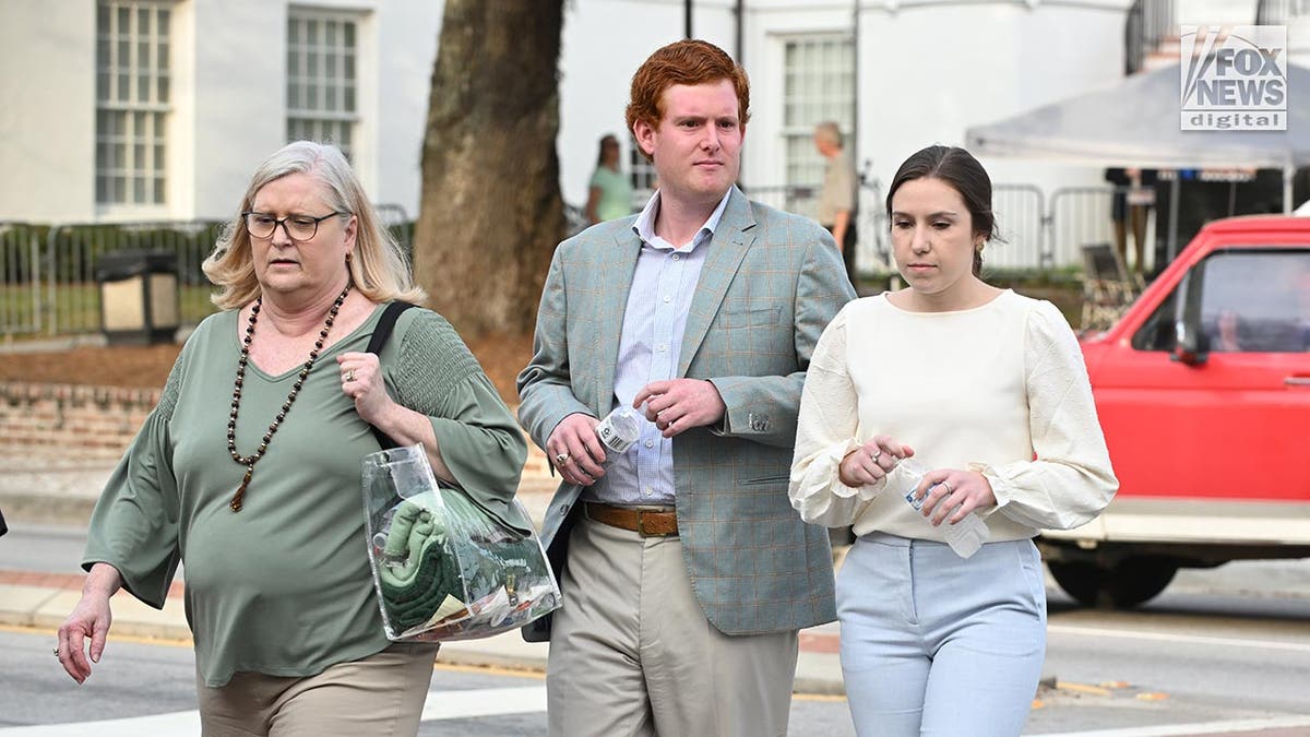 Buster and Brooklyn walk along holding water bottles, Lynn walks slightly ahead with a clear tote bag