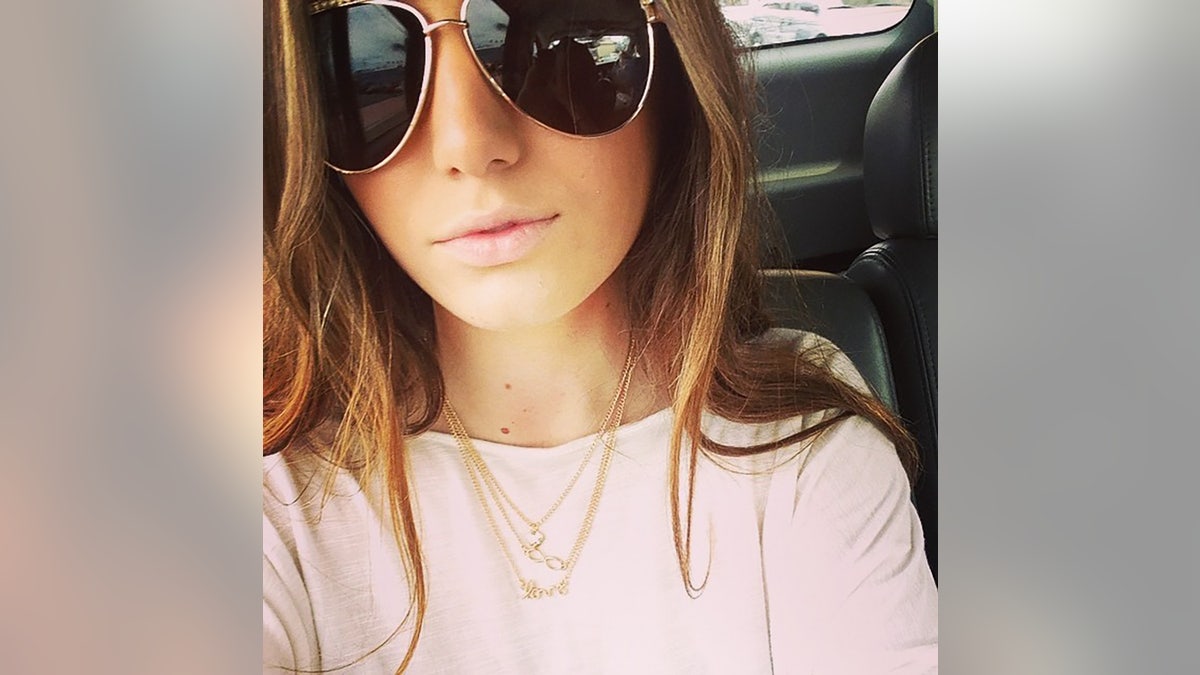 A close-up of Baylee Despot wearing a pink sweater and a gold chain with aviator glasses.