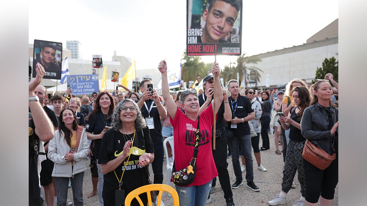 People cheer and hold up signs in Hostages Square in Tel Aviv ahead of Edan Alexander's expected release.
