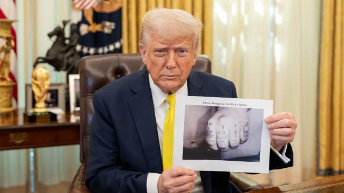 Trump holding up photo of tattoos