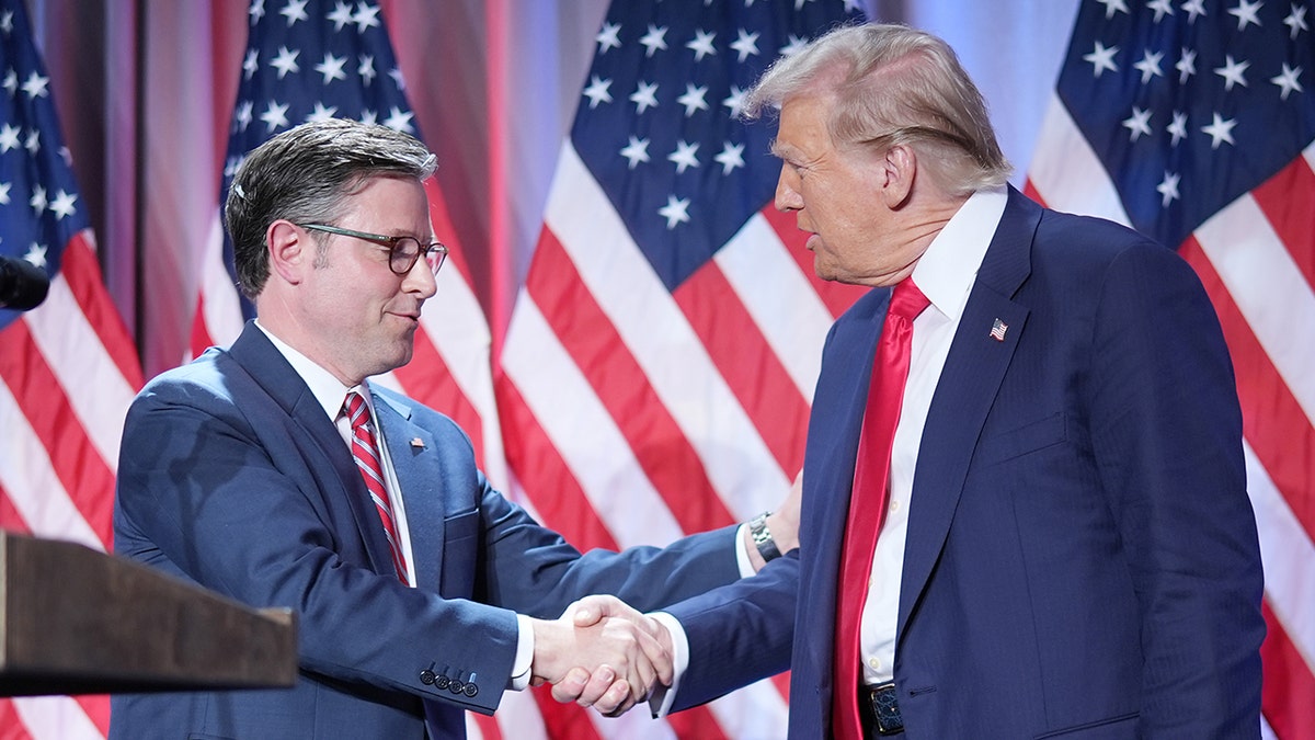 Mike Johnson, President Trump shake hands at lectern, US flags behind them
