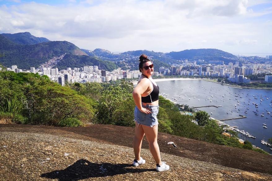 A woman with her arms up and back facing the camera with a view of a city in the background