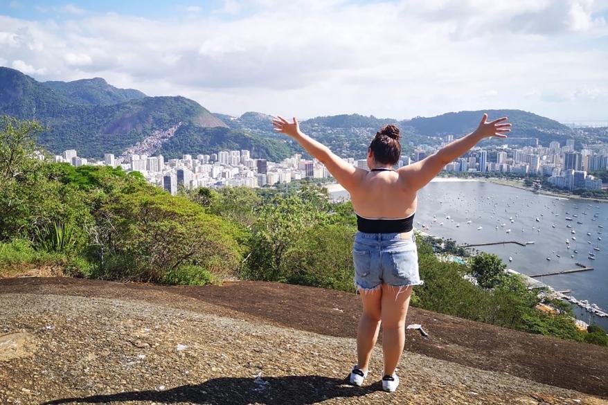 A woman with her arms up and back facing the camera with a view of a city in the background