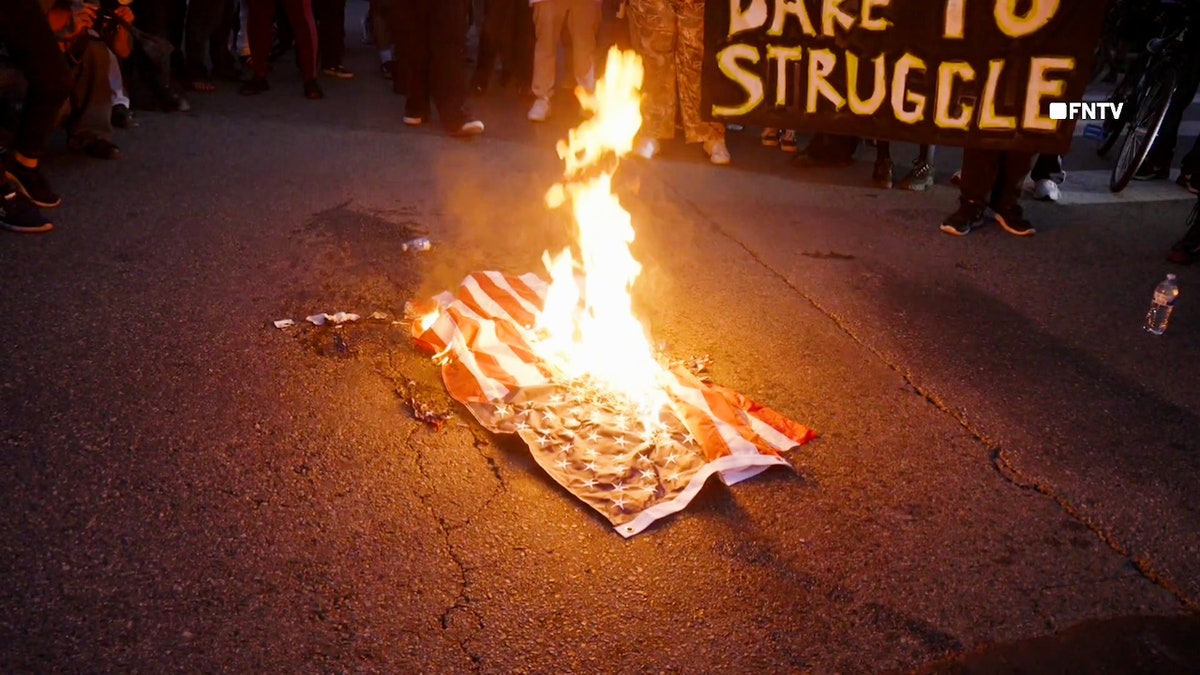 An American flag burns on the ground in Los Angeles.