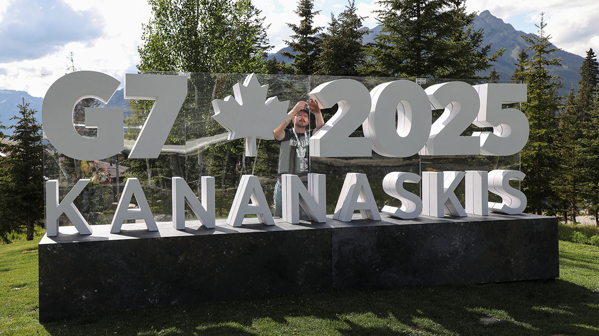 A worker prepares a sign ahead of the G7 summit