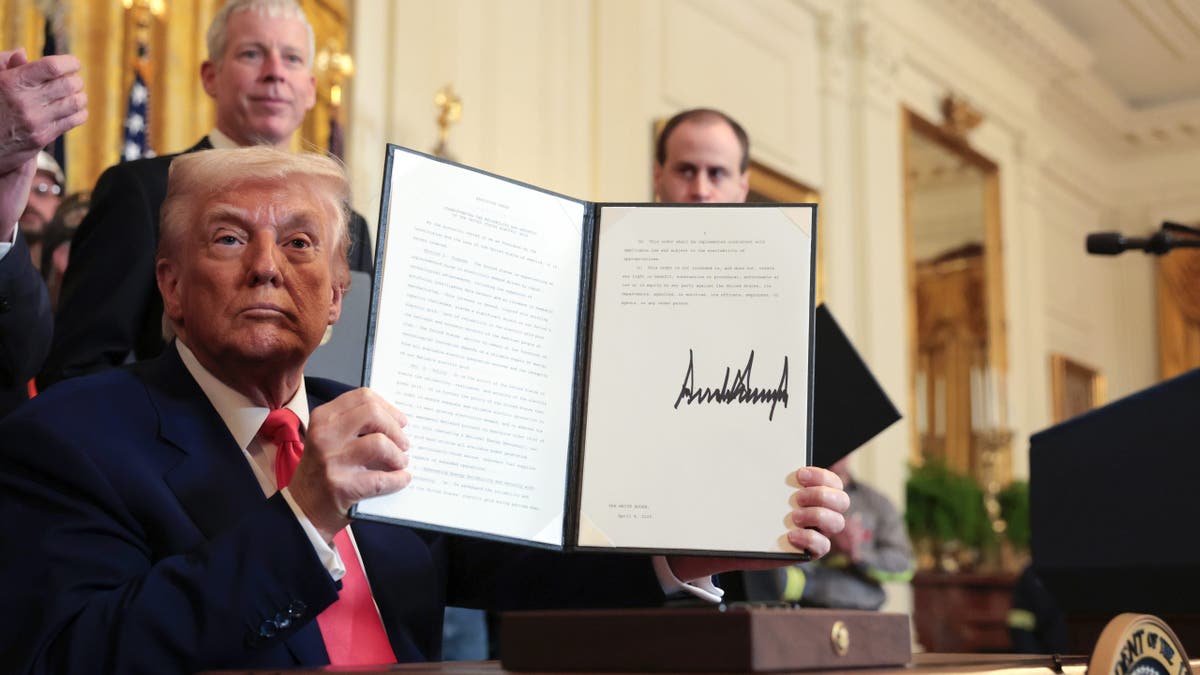 Trump holding up a signed executive order