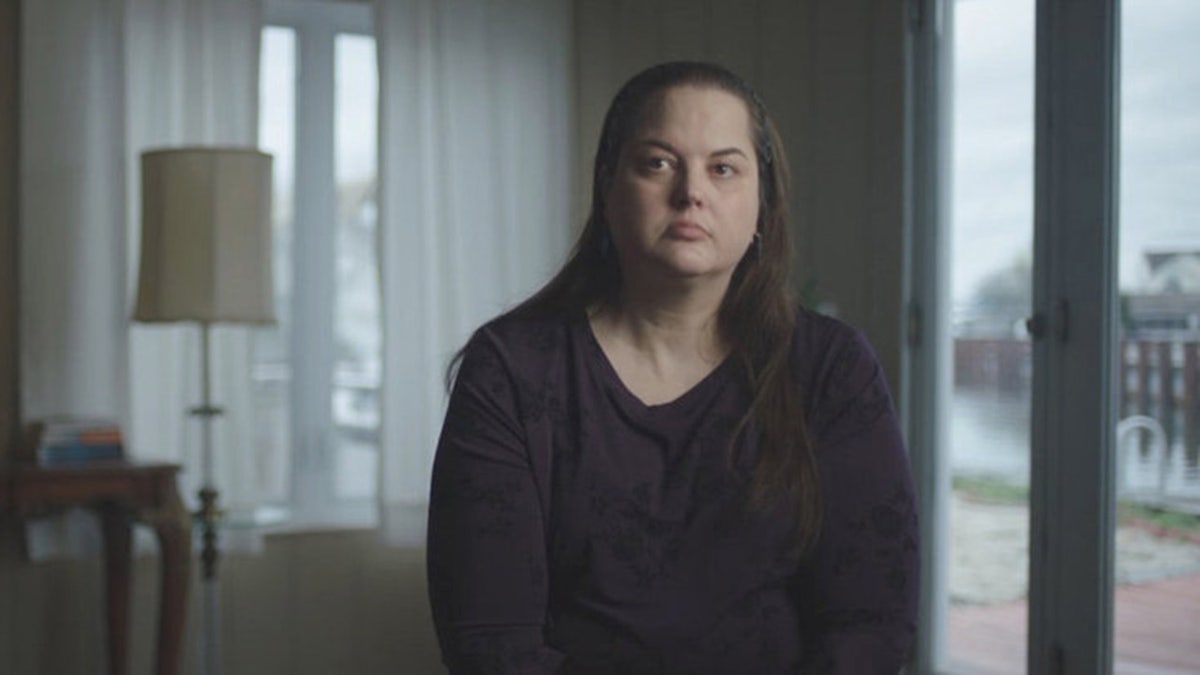 Kerri Rawson wearing a black sweater and sitting down looking serious.