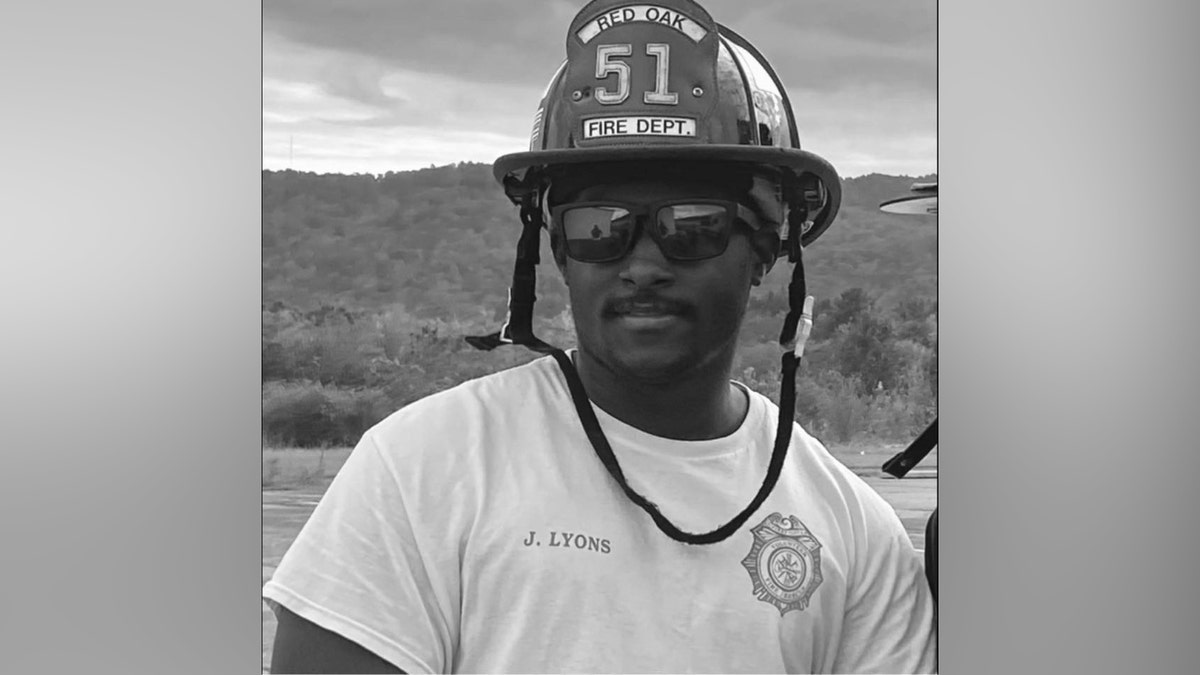 A black-and-white photo of Jay Lyons wearing a fireman hat