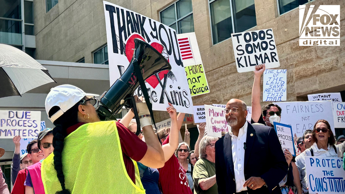 Demonstrators rally outside a courthouse holding signs in support of Kilmar Garcia and due process rights. A woman uses a megaphone while others raise signs reading