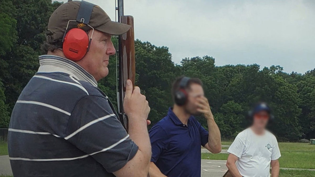 Rex Heuermann holding a gun next to two men at a shooting range.