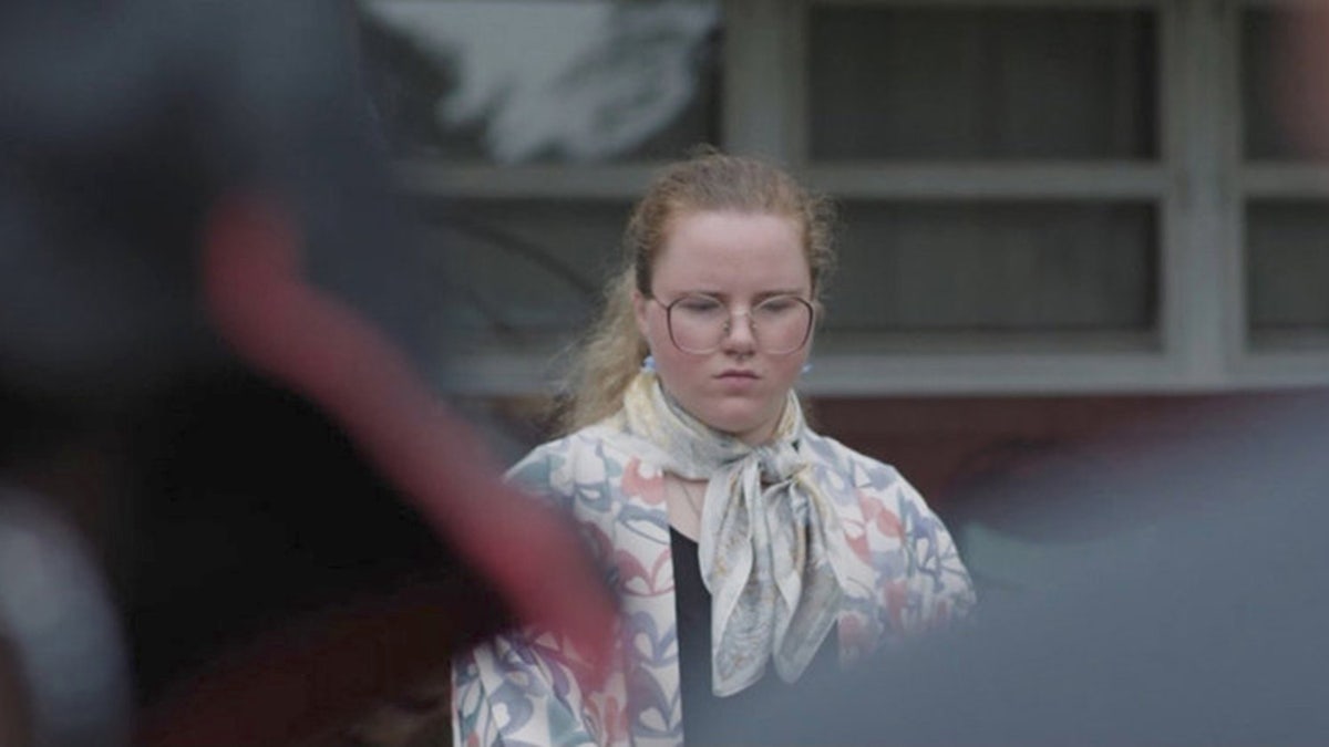 Victoria Heuermann looking down wearing a floral blouse and glasses.