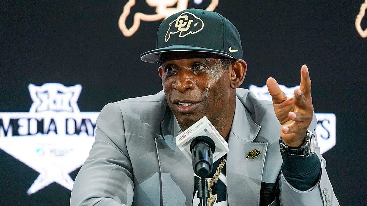 Deion Sanders talks with the media