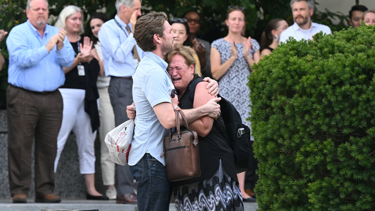 Fired State Department workers hug as supporters applaud during mass layoffs at Foggy Bottom headquarters on July 11, 2025.