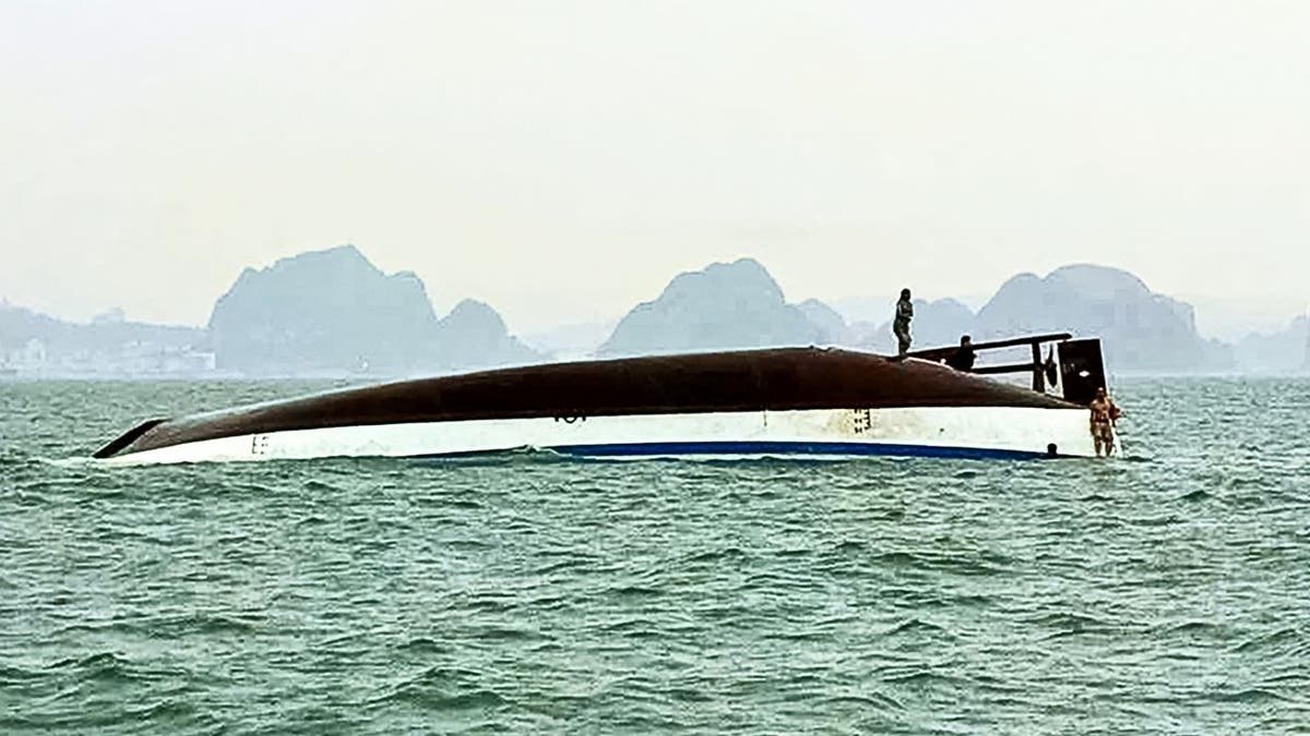 People stand on a capsized tourist boat