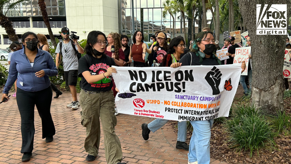 Protesters hold a "No ICE on campus!" sign outside Turning Point USA's Student Action Summit. 