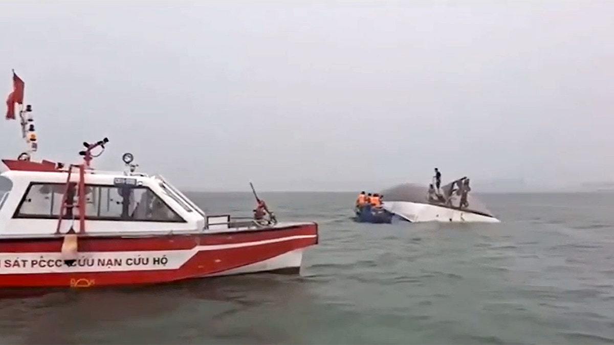 A rescue boat in the foreground of a capsized boat