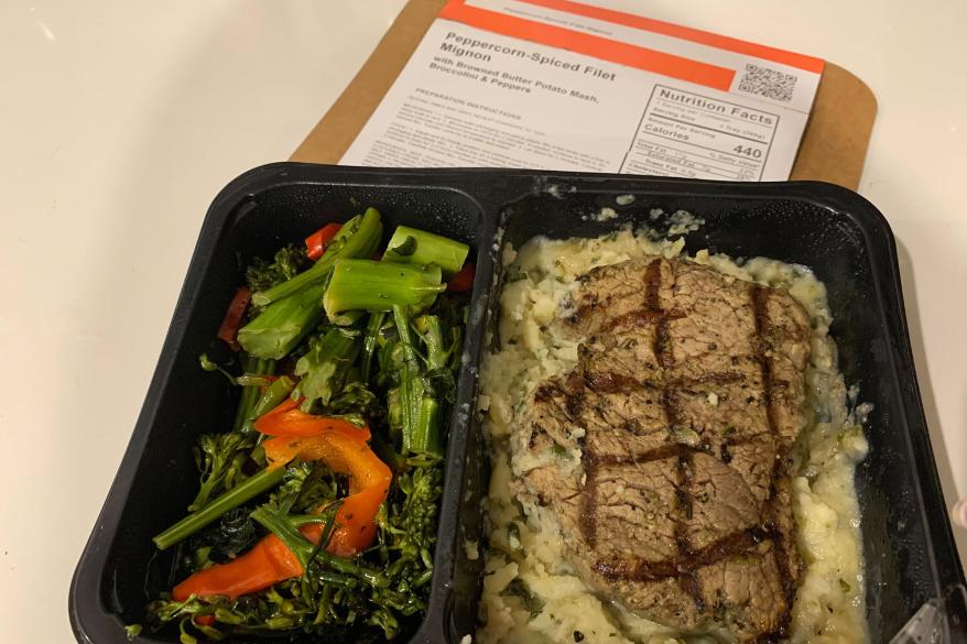 A steak and potatoes in a tray