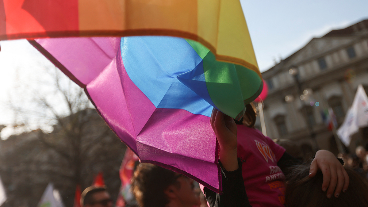 A child touches the LGBT flag at a protest rally in Milan