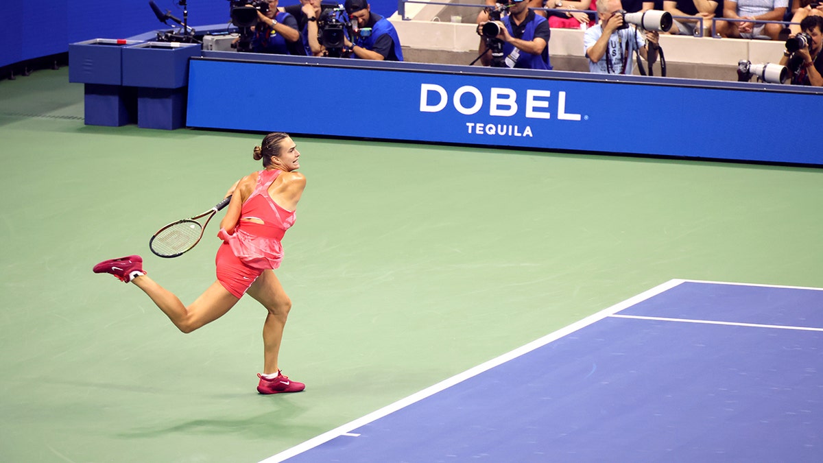 Aryna Sabalenka playing during tennis match at the US open in 2023, with Dobel Tequila ad in background