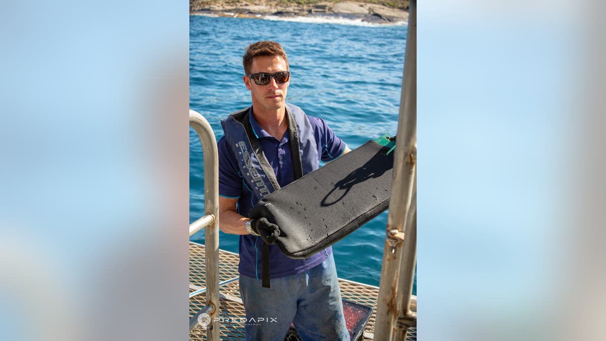 Flinders University Professor Charlie Huveneers holding wetsuit material