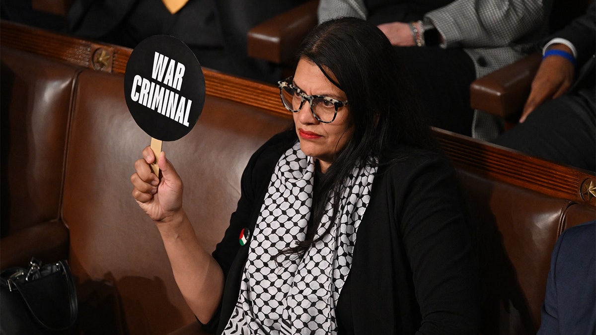 Rashida Tlaib seated, holding a "war criminal" sign during Israeli Prime Minister Benjamin Netanyahu's speech to Congress.