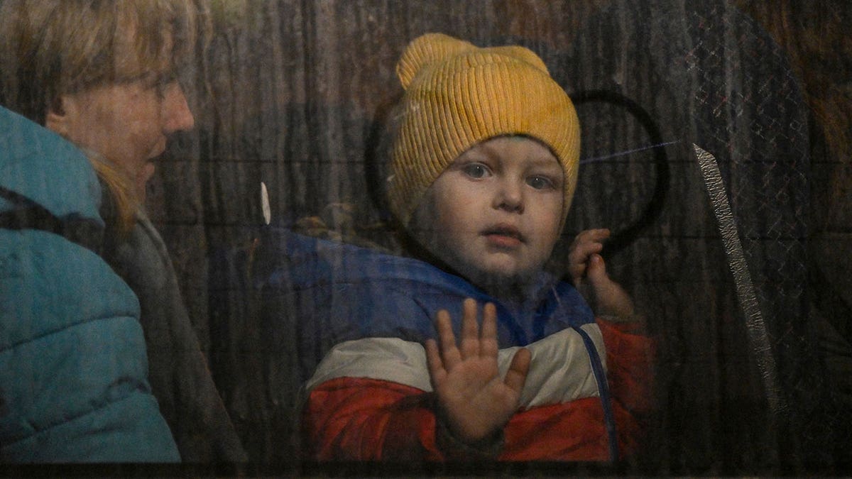 Ukrainian child presses hand against bus window