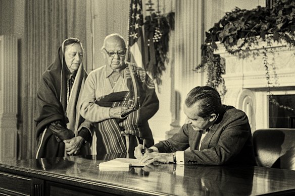 US President Richard Nixon signs a bill  in 1970 to the Taos Pueblo people the title to 48,000 acres of land in New Mexico, watched by an interpreter and tribal leader Juan de Jesus Romero. 